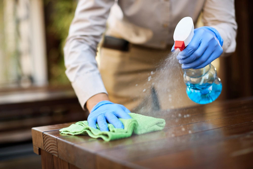 Main d'un technicien Steev Clean nettoyant une table à Lyon