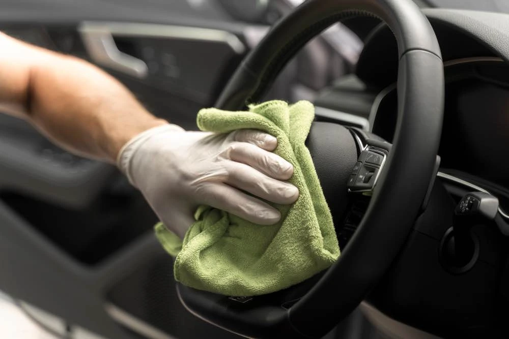 Main avec chiffon nettoyant l'intérieur d'une voiture à Lyon par Steev Clean